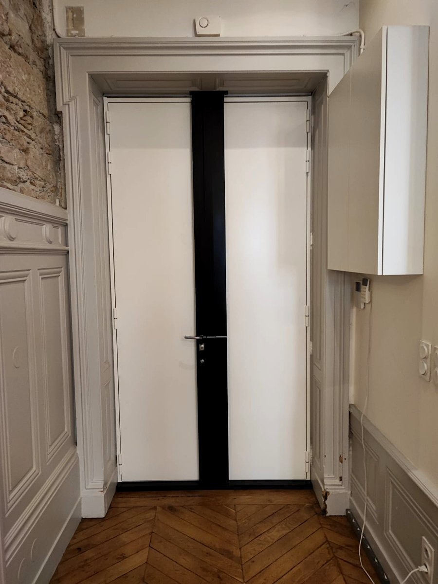 Porte blindée noire posée dans un immeuble haussmannien